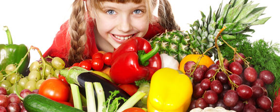 Mädchen lukt hinter Obst und Gemüse hervor