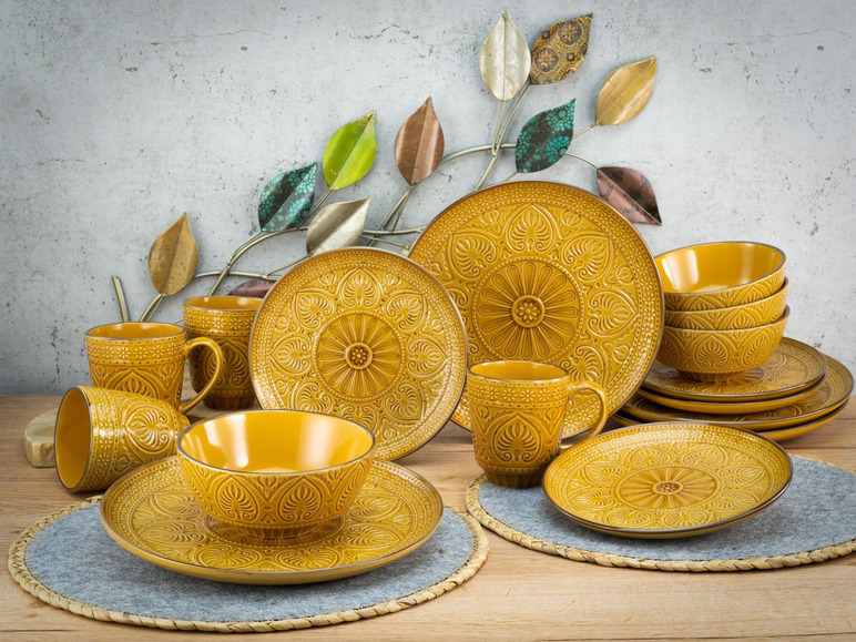 Ein Set mit goldenem Geschirr, inklusive Teller, Schalen und Tassen, mit einem ethnischen Muster.