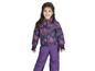 Ein Mädchen trägt eine violette Skihose und eine blaue Jacke mit Blumenmuster.