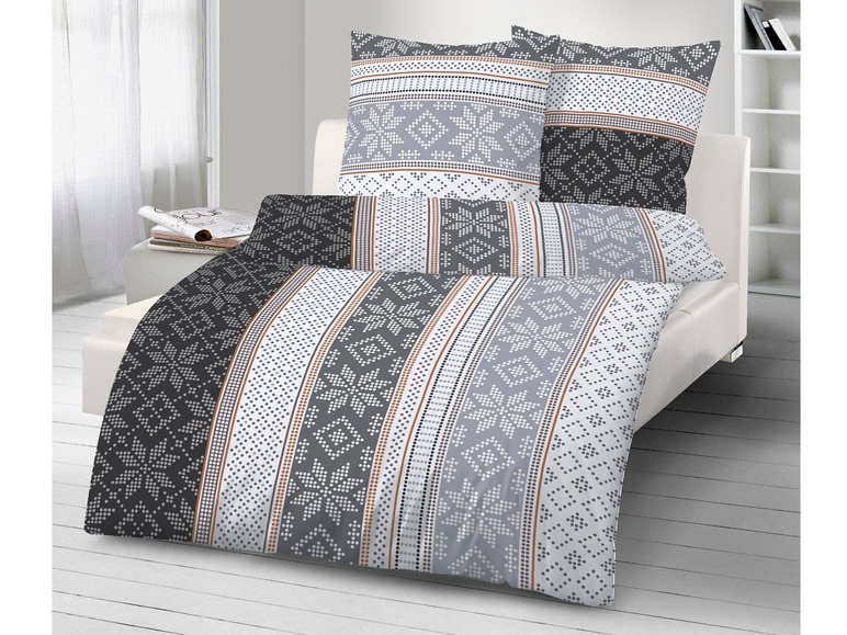 Ein Bett mit grau-weißem Bettzeug mit skandinavischem Muster.