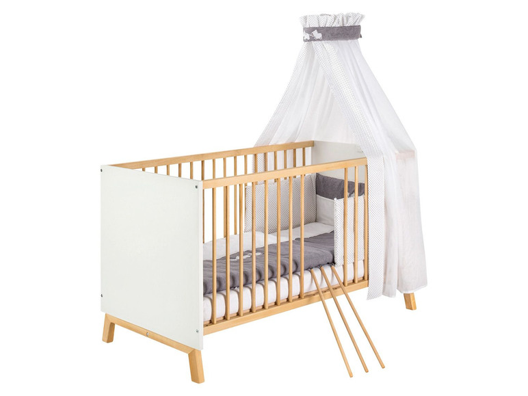 Ein Holzbabybett mit weißer Bettwäsche und Himmel.