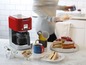 Ein rotes Kenwood kMix Kaffeemaschine, Kuchen und Tassen auf einer Arbeitsplatte.