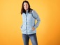 Eine Frau trägt eine blaue Daunenweste und Jeans.