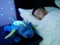 Ein blauer Drache mit Sternenprojektor neben einem schlafenden Jungen.