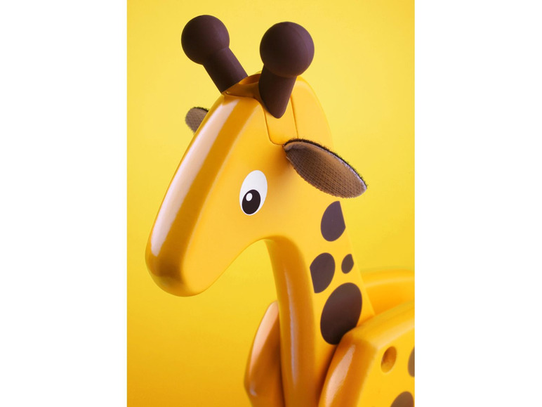 Eine gelbe Holz-Giraffe mit braunen Flecken.
