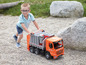 Ein Junge schiebt einen orangefarbenen Spielzeug-Müllwagen.