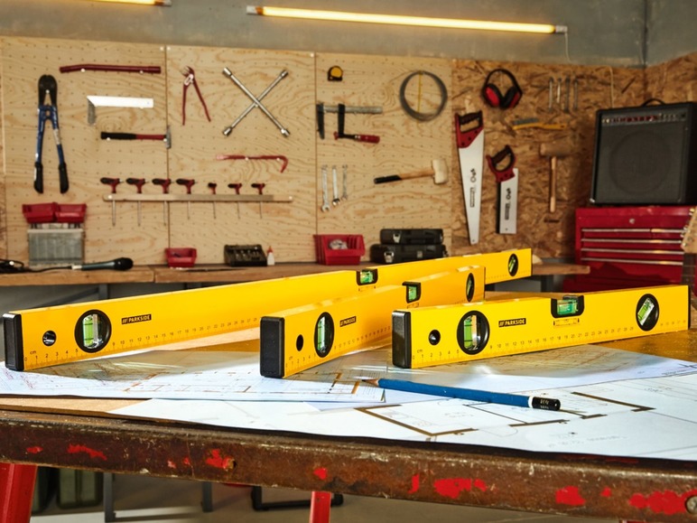 Drei gelbe Wasserwaagen von Parkside auf einem Tisch mit Bauplänen.