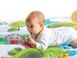 Ein Baby liegt auf einer bunten Spielmatte mit Tiermotiven.