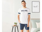 Mann in weißem T-Shirt mit 'New York' Aufdruck und blauen Shorts.