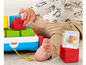 Ein Baby spielt mit Fisher-Price Bausteinen und einem Spielzeugwagen.