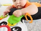 Ein Baby spielt mit einer Fisher-Price Spieldecke mit einem Blatt-Spielzeug.