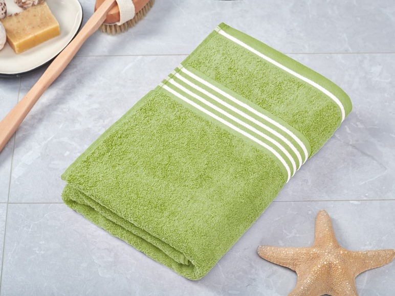 Ein grünes Handtuch mit weißen Streifen auf einem Fliesenboden.