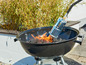 Ein Holzkohlegrill mit Kohle, die mit einem Feuerzeug angezündet wird.