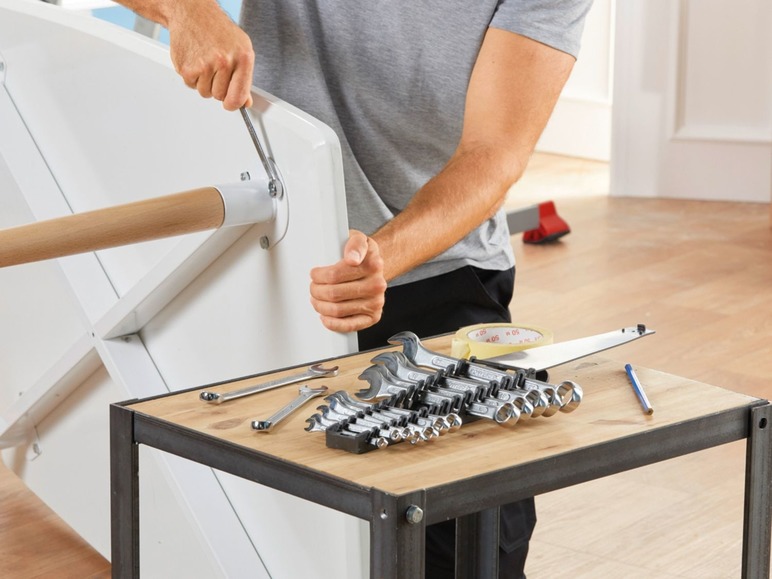 Ein Mann montiert einen Tisch mit einem Werkzeugset und einem Schraubendreher.