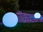 Zwei runde, weiße LED-Gartenleuchten auf Kies.