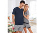 Ein Paar in passenden Pyjamas, er trägt ein dunkelblaues T-Shirt mit kurzen Ärmeln und graue Shorts, sie ein gestreiftes T-Shirt mit kurzen Ärmeln und Shorts mit Spitze.