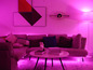 Ein rosa Wohnzimmer mit einem Sofa, einem Couchtisch und LED-Beleuchtung.