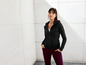 Eine Frau trägt einen schwarzen Hoodie und eine bordeauxrote Hose.