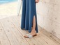 Eine Frau trägt ein langes blaues Kleid und Sandalen auf einem Holzboden.