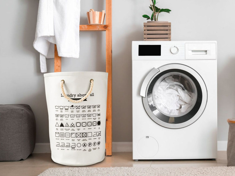 Ein weißer Wäschekorb mit Waschanleitung und eine Waschmaschine im Badezimmer.