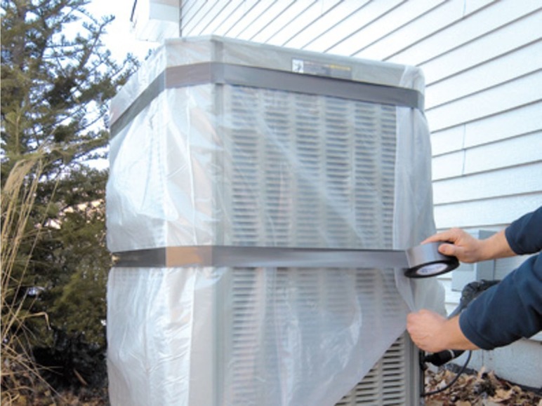 Eine Klimaanlage wird mit Plastikfolie und Klebeband abgedeckt.