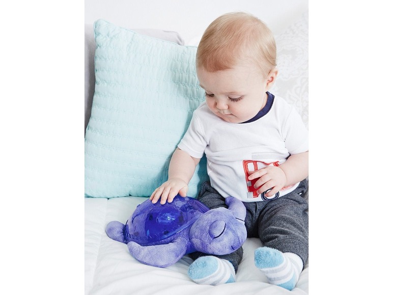 Ein Baby berührt eine blaue Schildkröten-Nachtlampe.