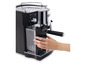 Eine schwarze Delonghi Espressomaschine mit einem Wassertank und einer Hand, die den Hebel bedient.