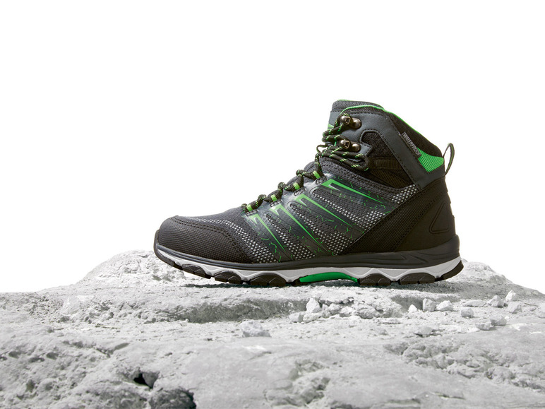 Ein schwarzer Wanderschuh mit grünen Akzenten auf einem steinigen Untergrund.