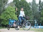 Eine Frau fährt Fahrrad mit einem Anhänger für Kinder.