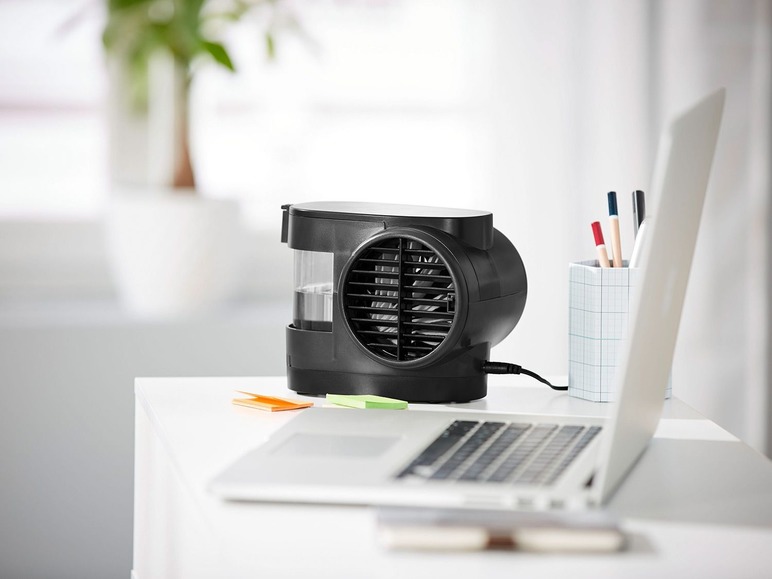 Ein kleiner, tragbarer Ventilator und ein Laptop auf einem Schreibtisch.