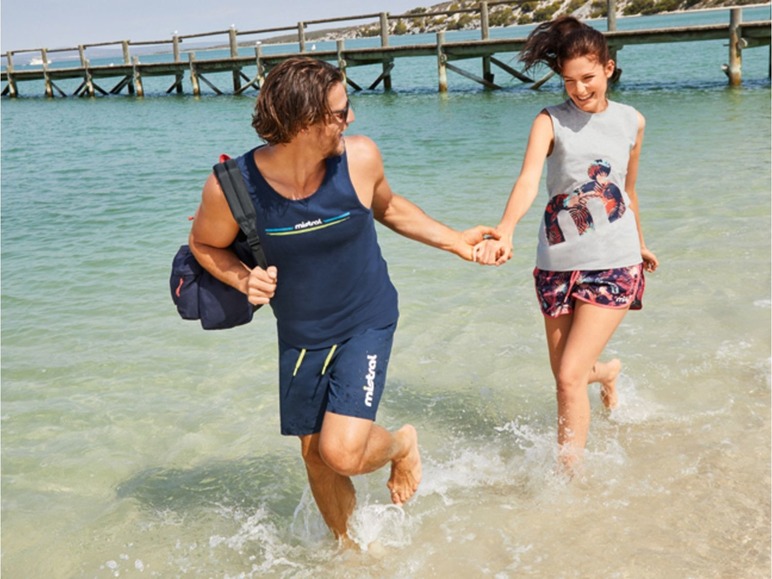 Ein Mann und eine Frau tragen Mistral-Kleidung, während sie am Strand rennen.
