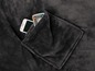 Eine graue Fleece-Decke mit einer Tasche für ein Telefon und eine Fernbedienung.