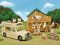 Ein Wohnmobil, ein Holzhaus und kleine Calico Critters Figuren.