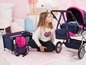 Ein Mädchen mit einem Puppenwagen, einem Puppenbett und einer Tragetasche mit Herzchenmuster.