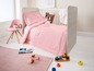 Ein rosa Babybett mit Bettdecke und Kissen, Spielzeug und einem rosa Stuhl