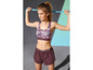 Eine Frau in Sport-BH und Shorts mit einem Trainingsband.