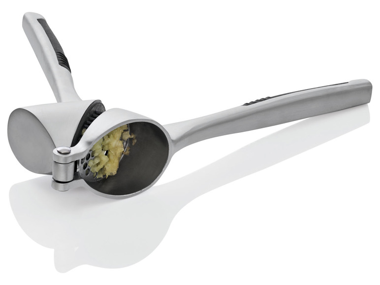 Ein silberner Knoblauchpresse mit gepresstem Knoblauch.