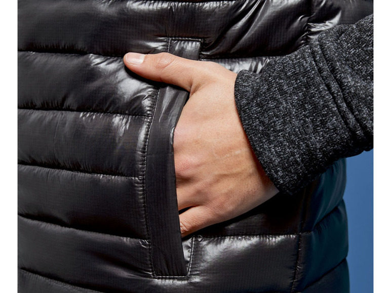 Nahaufnahme einer schwarzen Daunenjacke mit einer Hand in der Tasche.