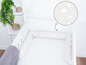 Ein weißes Babybett mit einer Sicherheitsumrandung mit Wolkenmuster.