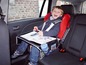 Ein Kind in einem Autositz mit einem Tisch zum Essen oder Malen.