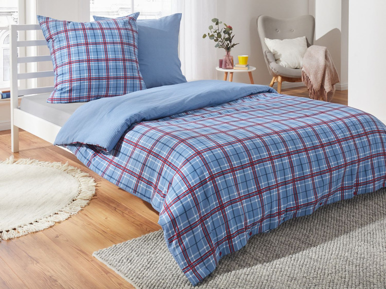 Ein Bett mit einer blau-roten karierten Bettdecke.