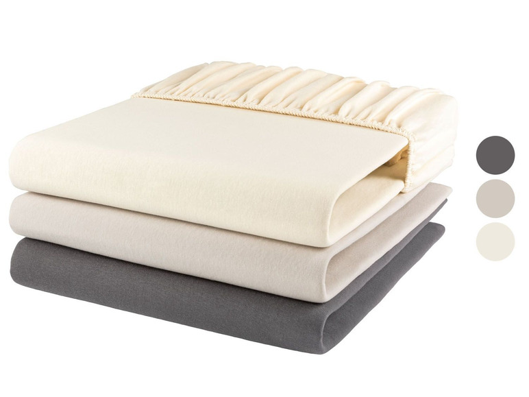 Drei Bettwäschelaken in Grau, Beige und Weiß.