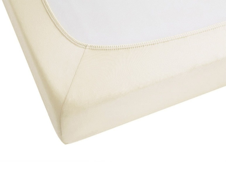 Ein cremefarbenes Spannbetttuch.