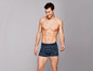 Mann trägt blaue Boxershorts mit tropischem Muster.