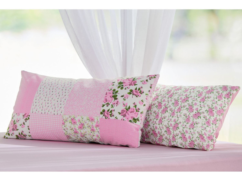 Zwei rosa Kissen mit Blumenmuster, eines im Patchwork-Stil.
