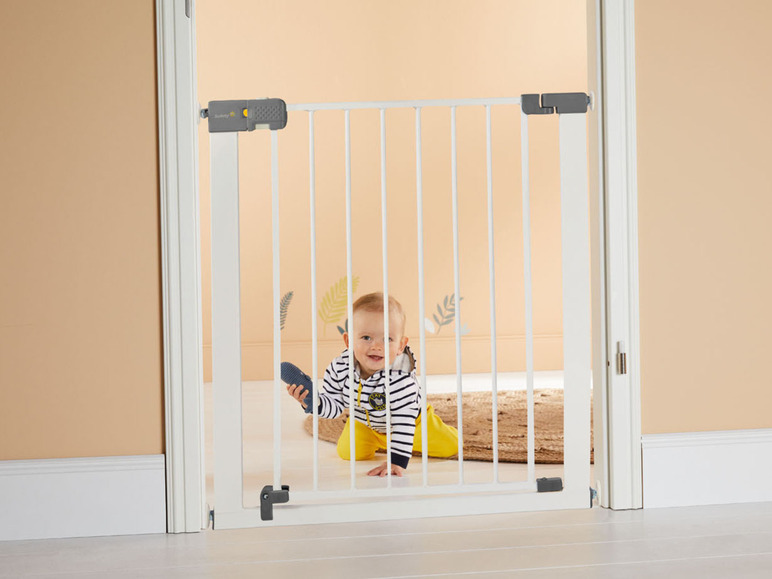 Ein Baby hinter einem weißen Sicherheitstor von Summer Infant.