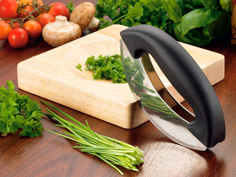 Ein Schneidebrett, ein Kräutermesser und frische Kräuter, bereit zum Kochen.