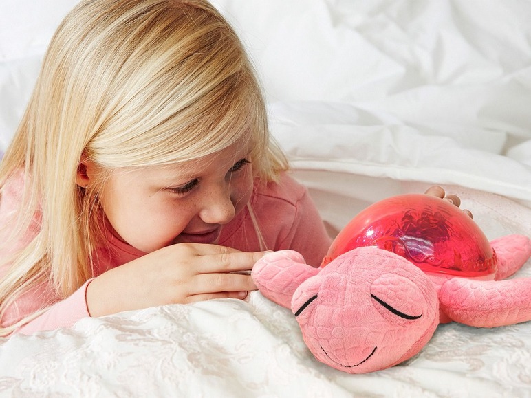 Ein Mädchen betrachtet eine rosafarbene Schildkröte mit Nachtlicht.