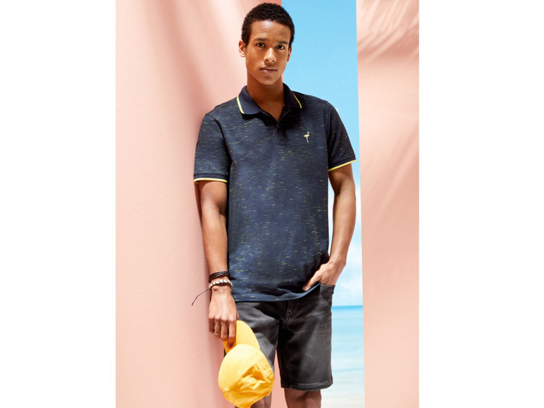 Mann trägt ein blaues Polohemd mit einem Flamingo und Shorts.