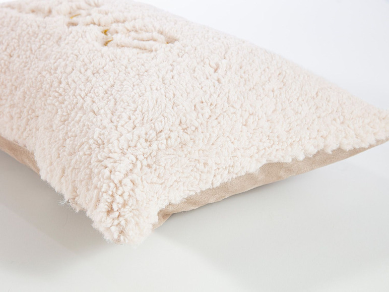 Ein cremefarbenes Kissen mit einem weichen, plüschigen Bezug.